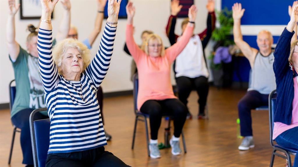 A group of senior adults doing chair-based exercises.